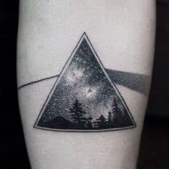 Tatuajes de pinos en el brazo y de bosque en la pierna